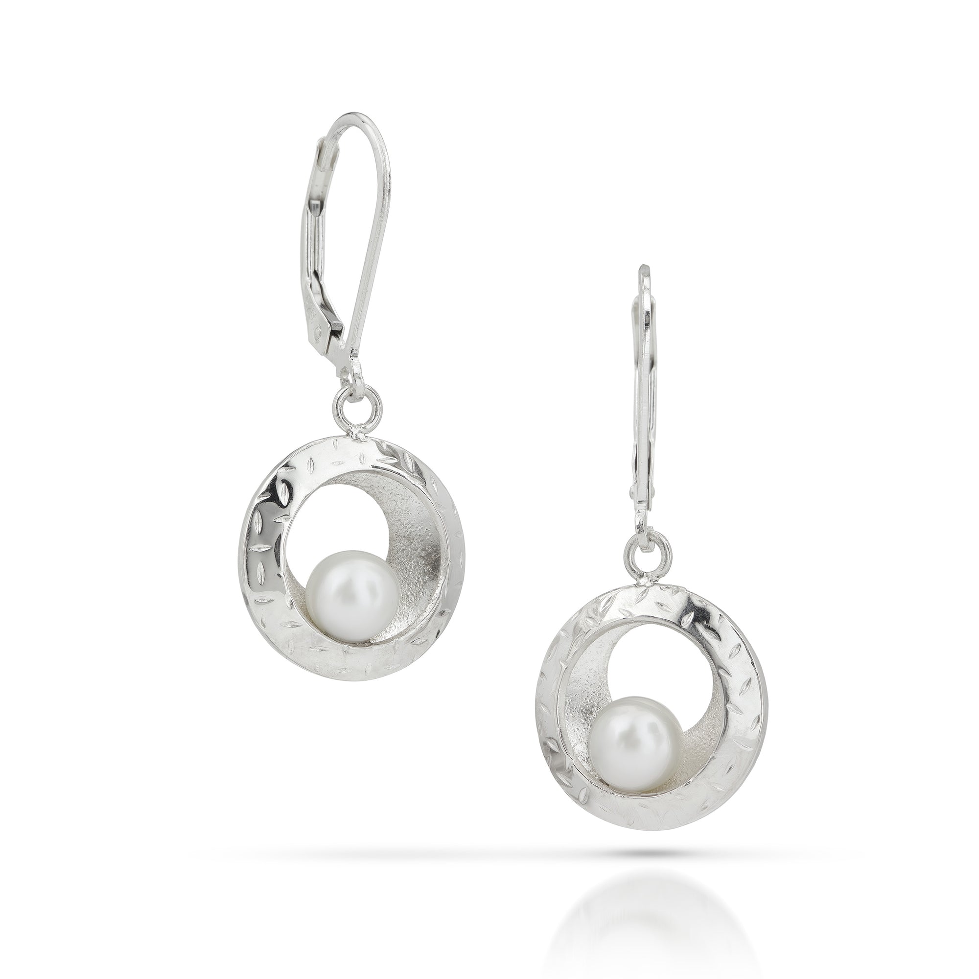 Silver dangle earrings with white pearls balancing on silver disc on a white background